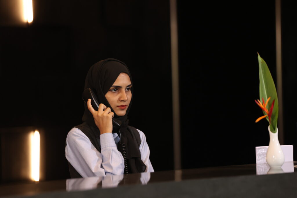 Hospitality staff member speaking on the phone at a hotel reception.